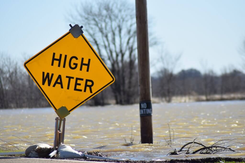 Dyersburg,,Tennessee/united,States-,March,12,,2012:,Mississippi,Flood,Water,Invade A yellow sign says "high water" in front of a flooded roadway backed by leafless trees.